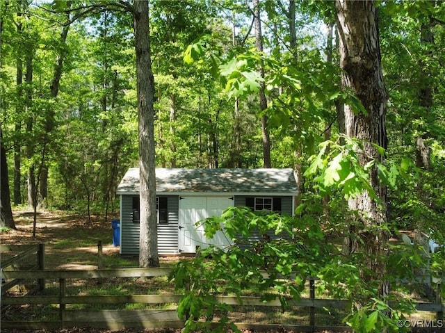 view of shed with a forest view and fence