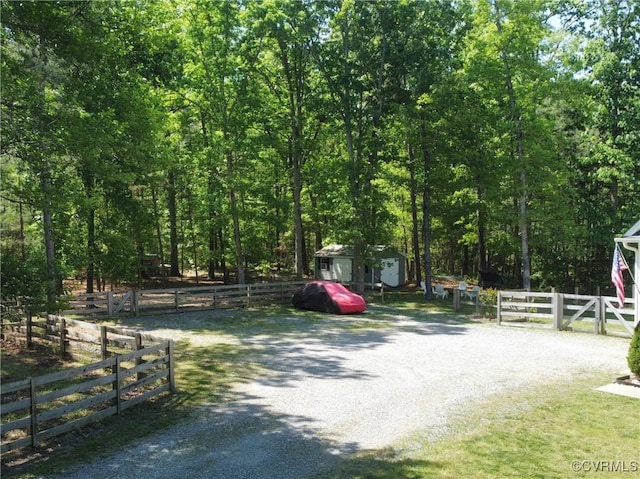 exterior space featuring a wooded view and gravel driveway