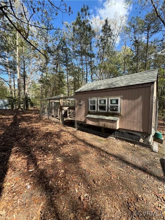 exterior space with an outdoor structure and roof with shingles