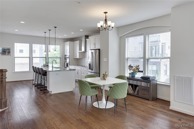 dining space featuring baseboards, a notable chandelier, dark wood finished floors, and visible vents