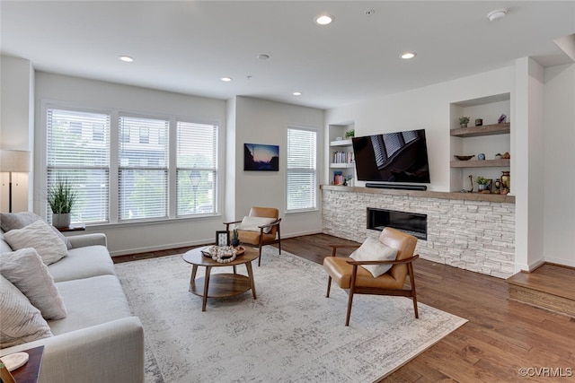 living room with built in shelves, baseboards, and wood finished floors