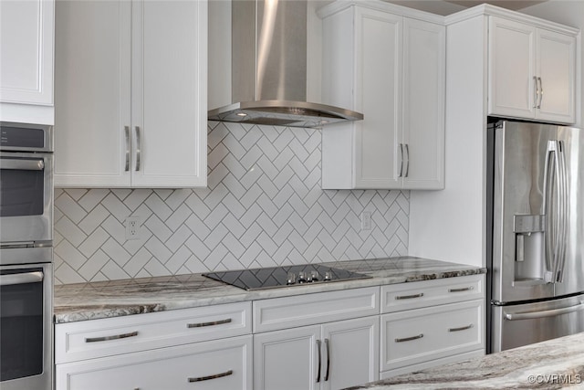 kitchen with decorative backsplash, wall chimney exhaust hood, appliances with stainless steel finishes, and white cabinetry