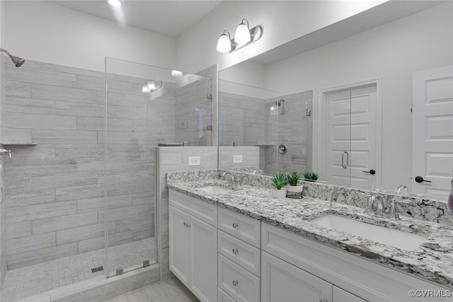 bathroom featuring double vanity, a sink, and a stall shower