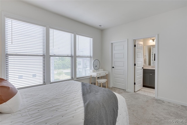 bedroom featuring baseboards, light colored carpet, and ensuite bathroom