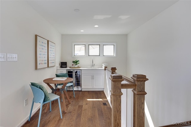 interior space with wood finished floors, a sink, baseboards, wine cooler, and recessed lighting