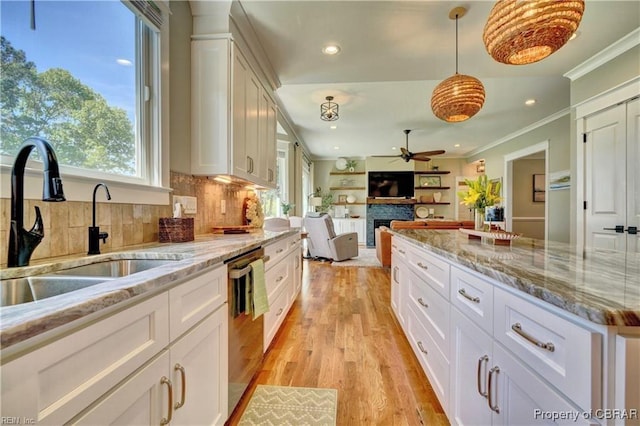 kitchen with stainless steel dishwasher, ornamental molding, ceiling fan, plenty of natural light, and backsplash