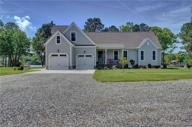 view of front facade with a shingled roof, a front yard, covered porch, and driveway