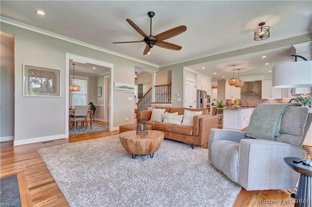 living area with stairs, recessed lighting, ceiling fan with notable chandelier, and light wood-style floors