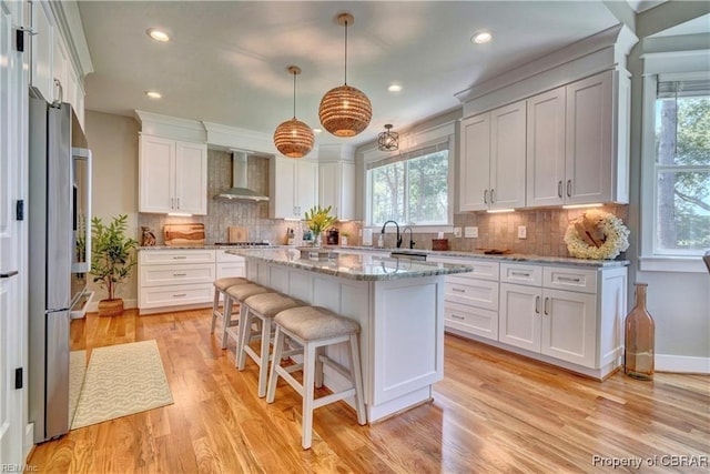 kitchen with wall chimney range hood, recessed lighting, and plenty of natural light