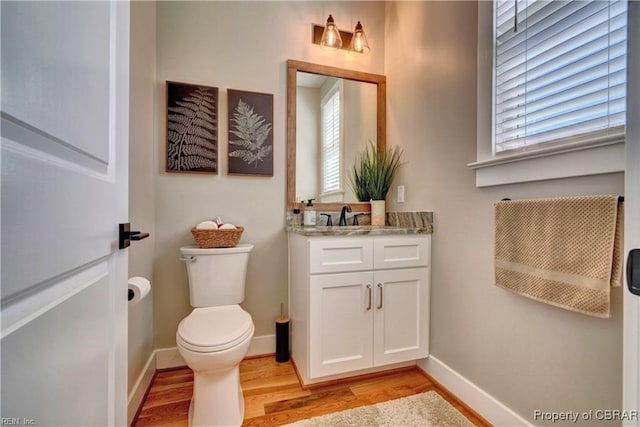 bathroom with vanity, baseboards, toilet, and wood finished floors