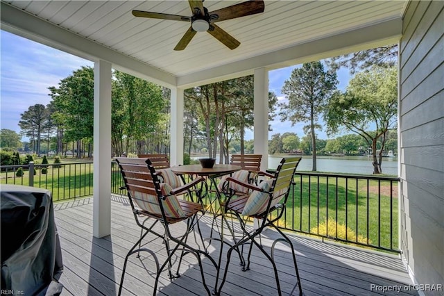 sunroom / solarium featuring outdoor dining area, a ceiling fan, a deck with water view, and wood finished floors