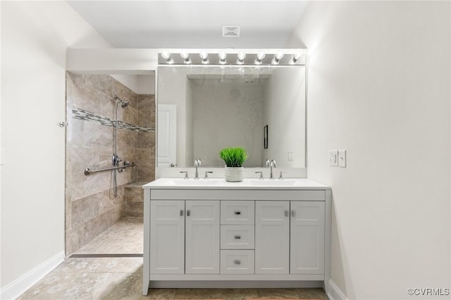 bathroom featuring a sink, baseboards, double vanity, and tiled shower