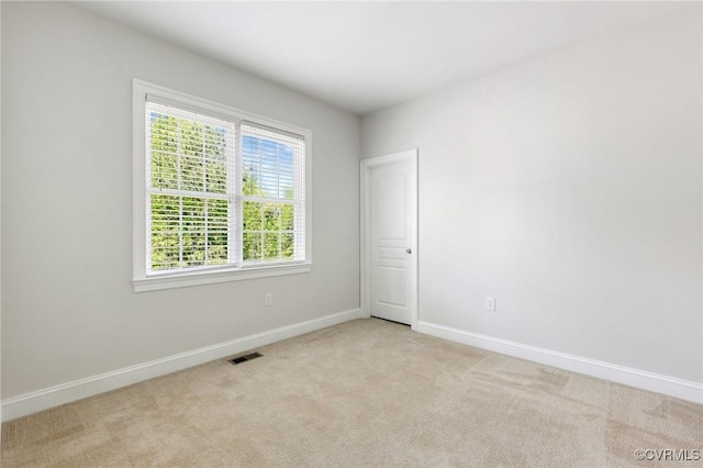 unfurnished room featuring baseboards, light colored carpet, and visible vents