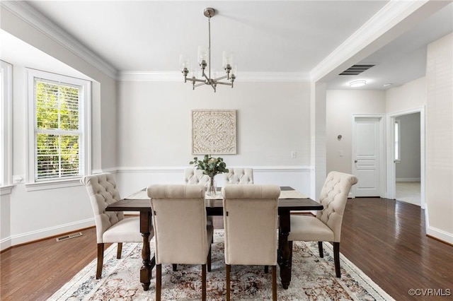 dining space with crown molding, a notable chandelier, wood finished floors, and visible vents