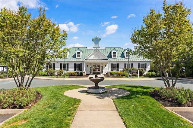 view of front of house with a standing seam roof, metal roof, and a front yard