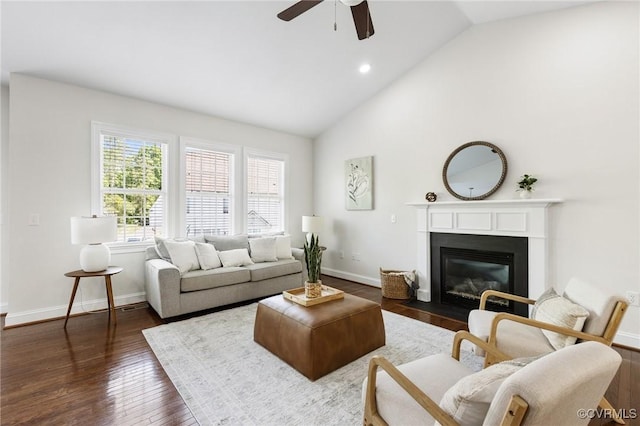 living area with ceiling fan, a fireplace with flush hearth, dark wood finished floors, baseboards, and high vaulted ceiling