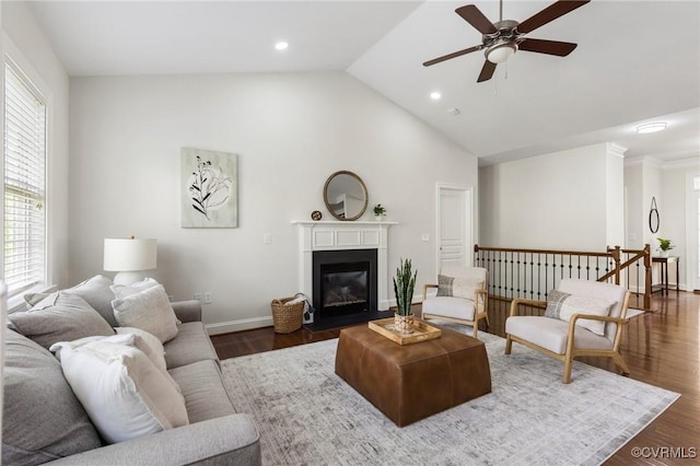 living area with ceiling fan, high vaulted ceiling, baseboards, a fireplace with flush hearth, and wood finished floors