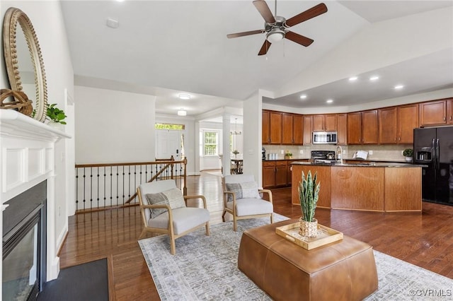 living area featuring ceiling fan, a fireplace with flush hearth, dark wood-style floors, and lofted ceiling