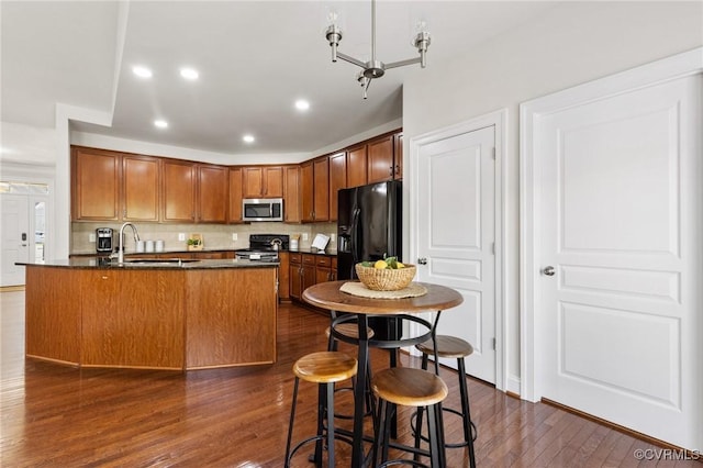kitchen with backsplash, dark countertops, appliances with stainless steel finishes, dark wood-style floors, and recessed lighting