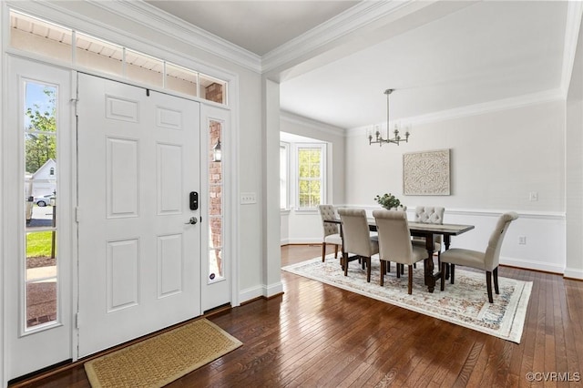 entryway featuring dark wood-type flooring, ornamental molding, baseboards, and a chandelier