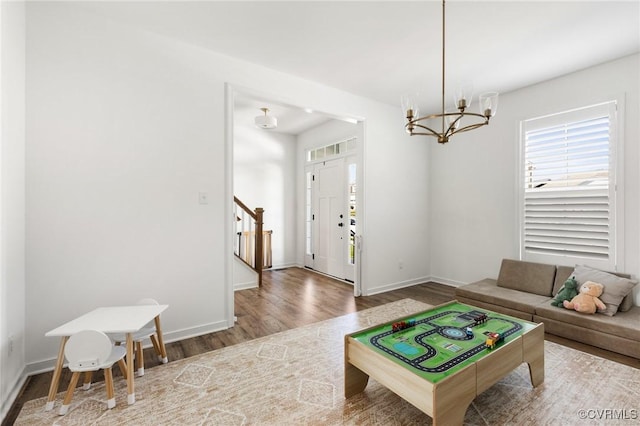rec room with baseboards, a chandelier, and wood finished floors