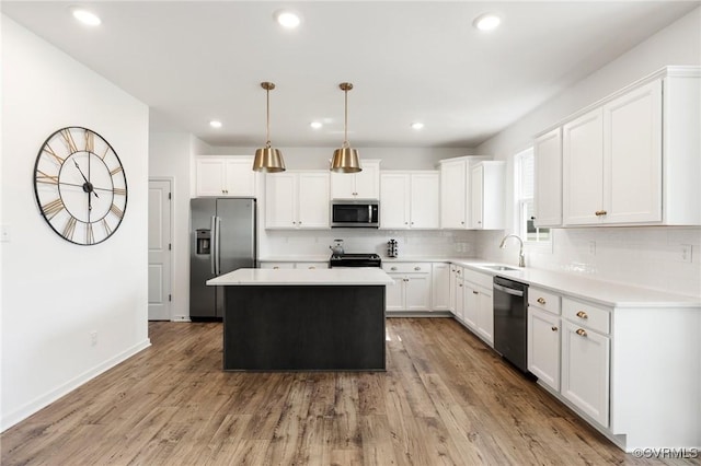 kitchen with decorative backsplash, a center island, light countertops, a sink, and stainless steel appliances