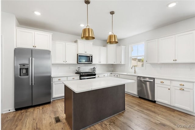 kitchen with backsplash, visible vents, a sink, stainless steel appliances, and white cabinetry