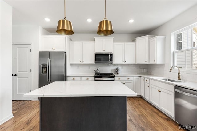 kitchen with a center island, white cabinetry, a sink, backsplash, and stainless steel appliances