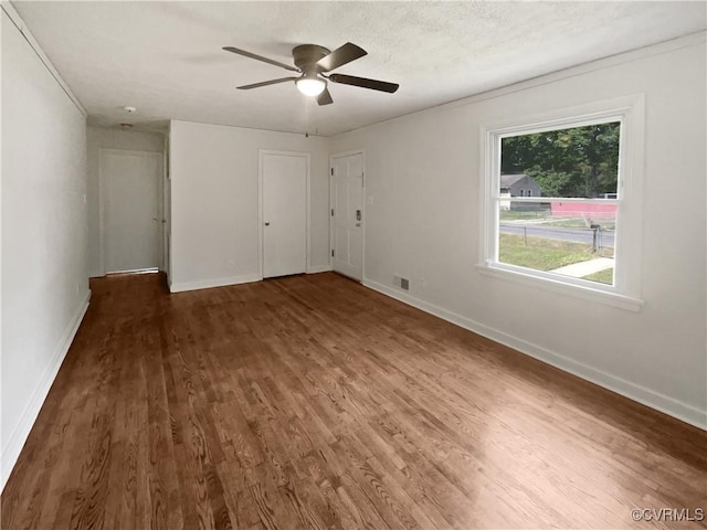 unfurnished bedroom featuring baseboards, ceiling fan, wood finished floors, and visible vents