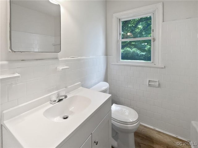 bathroom with wainscoting, vanity, toilet, tile walls, and wood finished floors