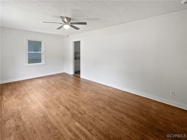 empty room featuring baseboards, a textured ceiling, ceiling fan, and wood finished floors
