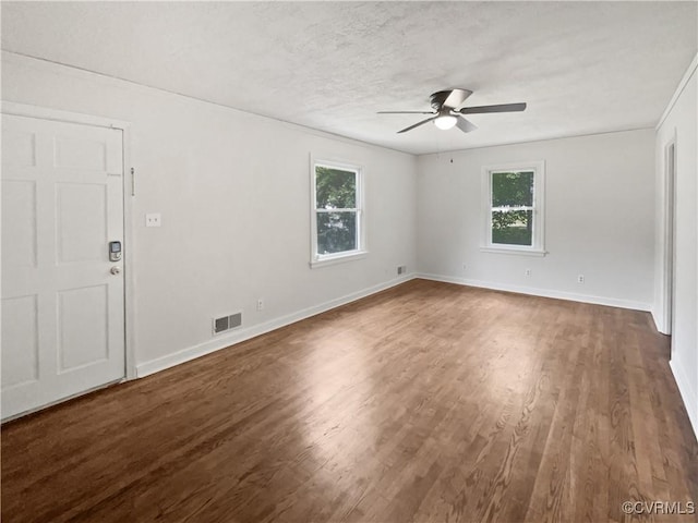 spare room featuring visible vents, ceiling fan, wood finished floors, and a wealth of natural light