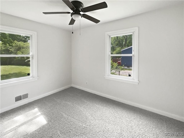 carpeted empty room with baseboards, plenty of natural light, ceiling fan, and visible vents