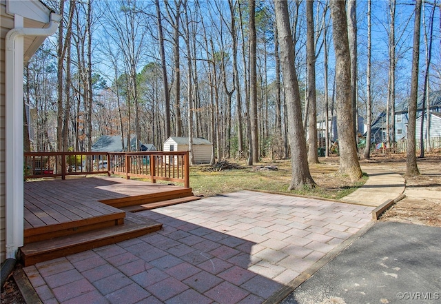 view of patio featuring a storage unit, a wooden deck, and an outbuilding