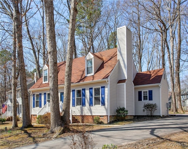new england style home with a chimney and aphalt driveway