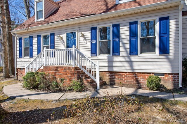 property entrance with roof with shingles and crawl space