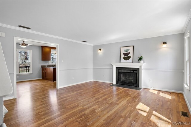 unfurnished living room featuring visible vents, a fireplace with flush hearth, light wood-style flooring, and crown molding
