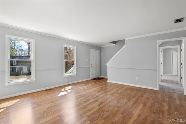 unfurnished living room featuring visible vents, ornamental molding, baseboards, and wood finished floors