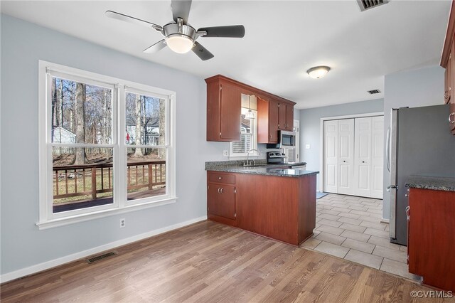 kitchen with ceiling fan, visible vents, appliances with stainless steel finishes, a sink, and a peninsula