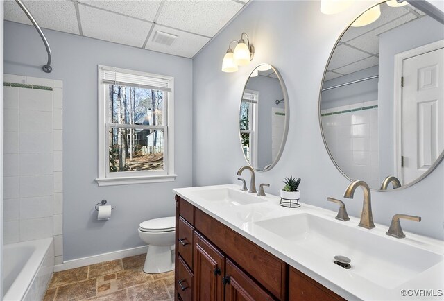 bathroom with a sink, baseboards, a drop ceiling, and toilet