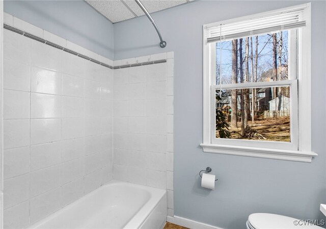 bathroom with baseboards, shower / bathtub combination, and toilet