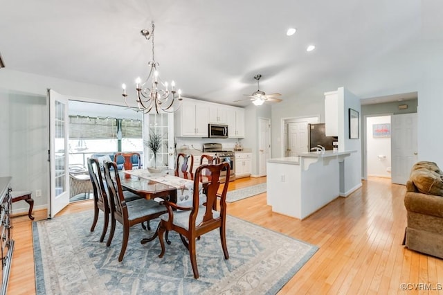 dining space with vaulted ceiling, baseboards, ceiling fan with notable chandelier, and light wood-style flooring