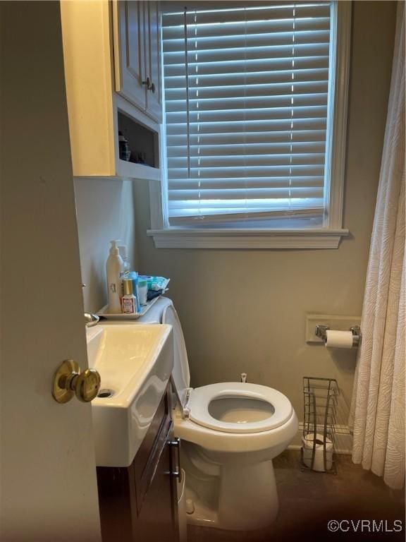 bathroom featuring toilet, vanity, and baseboards