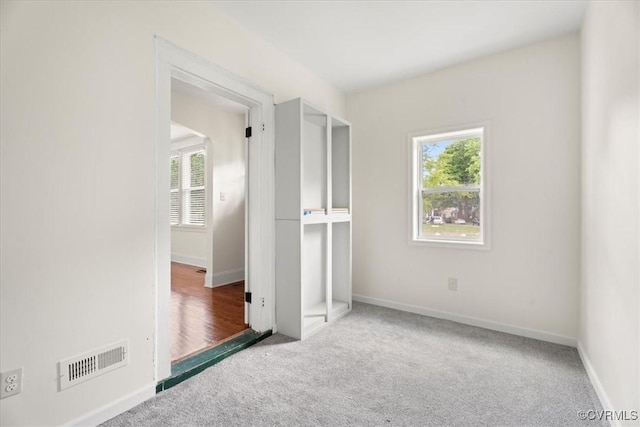 unfurnished bedroom with visible vents, multiple windows, and carpet