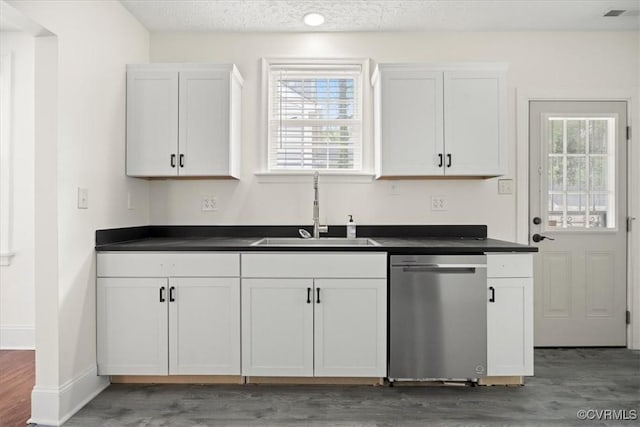 kitchen with light wood-style floors, a sink, dishwasher, and dark countertops