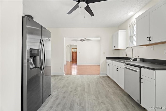 kitchen featuring a sink, appliances with stainless steel finishes, a ceiling fan, and dark countertops