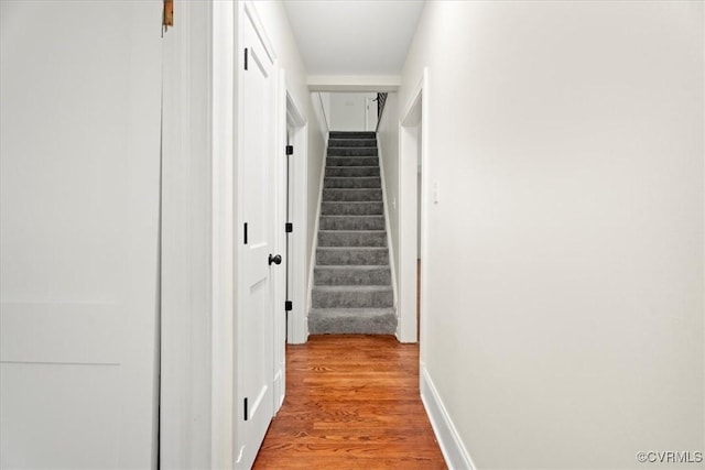 hallway with stairway, baseboards, and wood finished floors