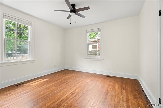 spare room with baseboards, ceiling fan, hardwood / wood-style floors, and visible vents