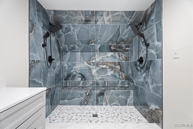 bathroom with a tile shower and vanity