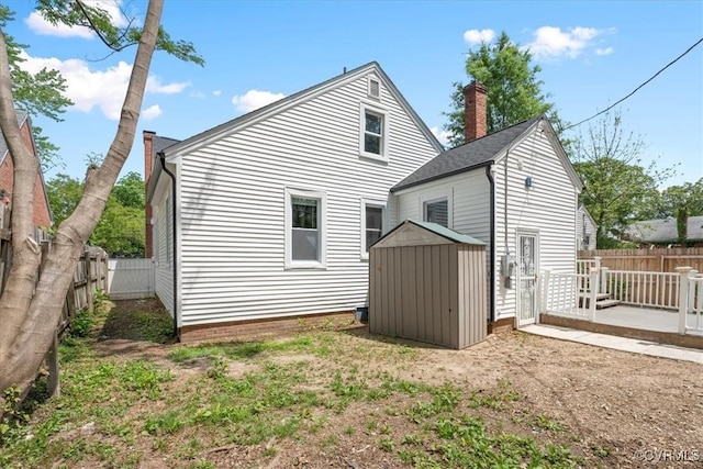 back of house featuring an outbuilding, a chimney, a fenced backyard, and a storage unit